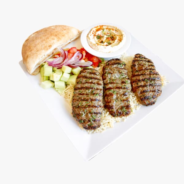 Three grilled Mediterranean kofta kebabs on rice with pita, hummus, and salad.